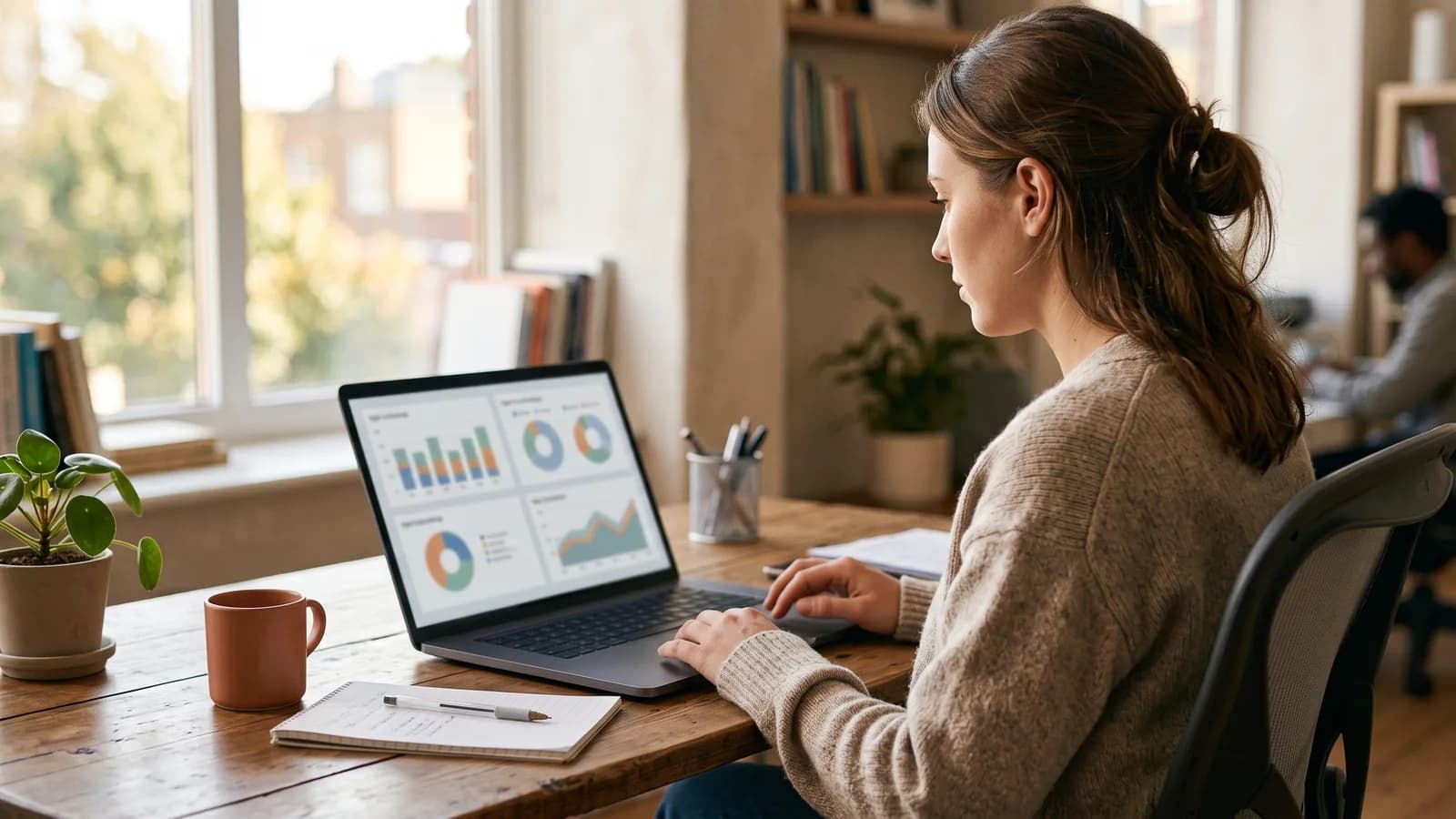 Marketing coordinator comparing social ad creative and search campaign dashboards side by side on a laptop.